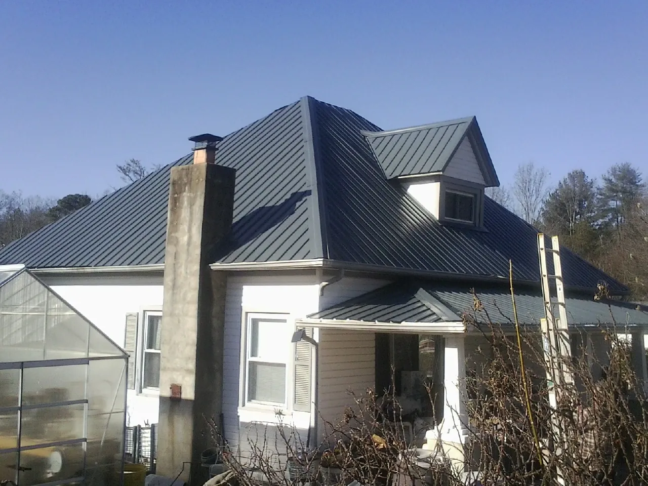 Dark blue standing seam metal roof on a white farmhouse with dormer — Slate & Tile Roof Repair by Roofing Brothers in Wonder Lake