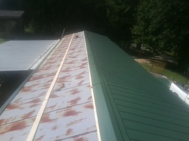 Old rusted panels beside newly installed green metal roofing — Wind Damage Roof Repair by Roofing Brothers in Wonder Lake