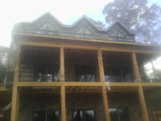 Dormers and porch framing on a large log home under construction — Roof Coating work by our crew in Wonder Lake