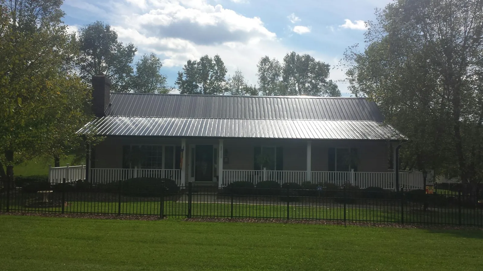 Gray metal roof on a brick ranch with a full width front porch — Gutter Guard Installation work by our crew in Wonder Lake