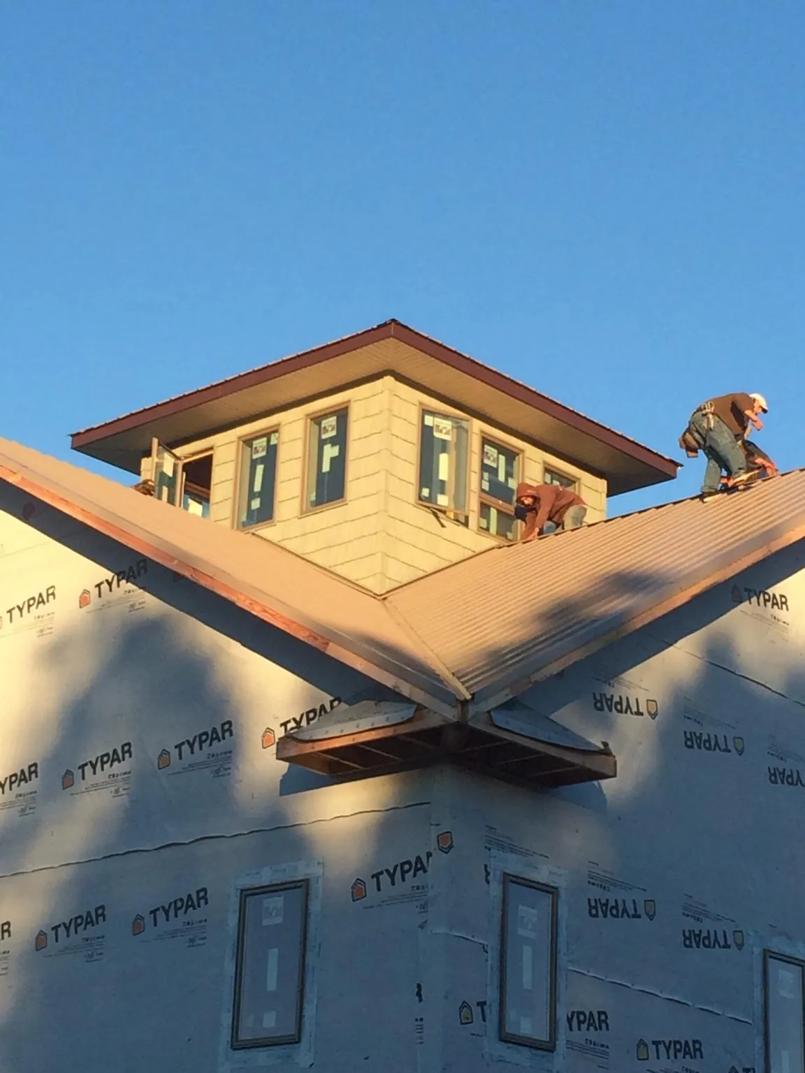 Roofers working around a rooftop cupola on a new metal roof at sunset — Roof Waterproofing in Wonder Lake by Roofing Brothers